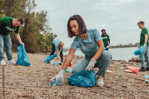 Volunteers picking up trash on a riverbank: promoting environmental awareness photo