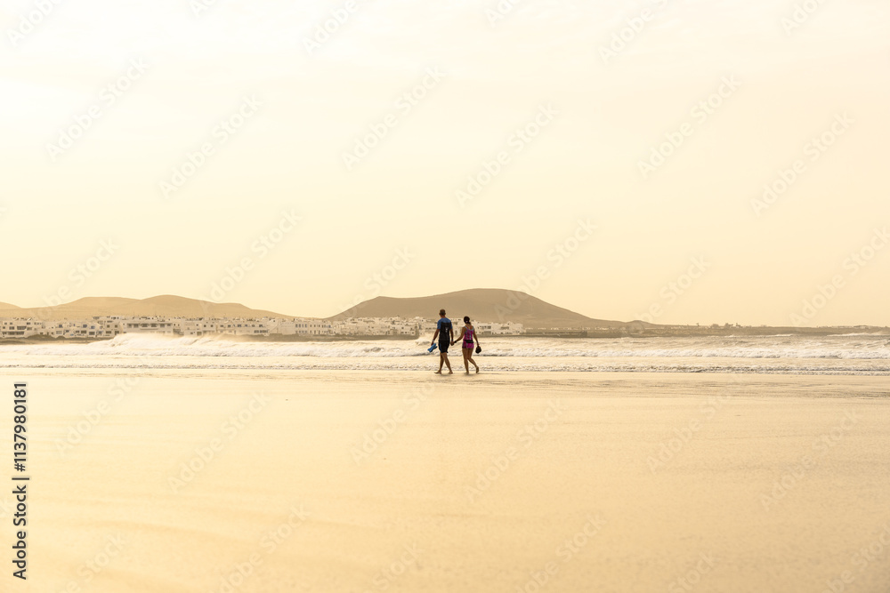 Beautiful couple walks along the seashore at sunset. Honeymoon. Beautiful couple walks along the seashore at sunset. Honeymoon.