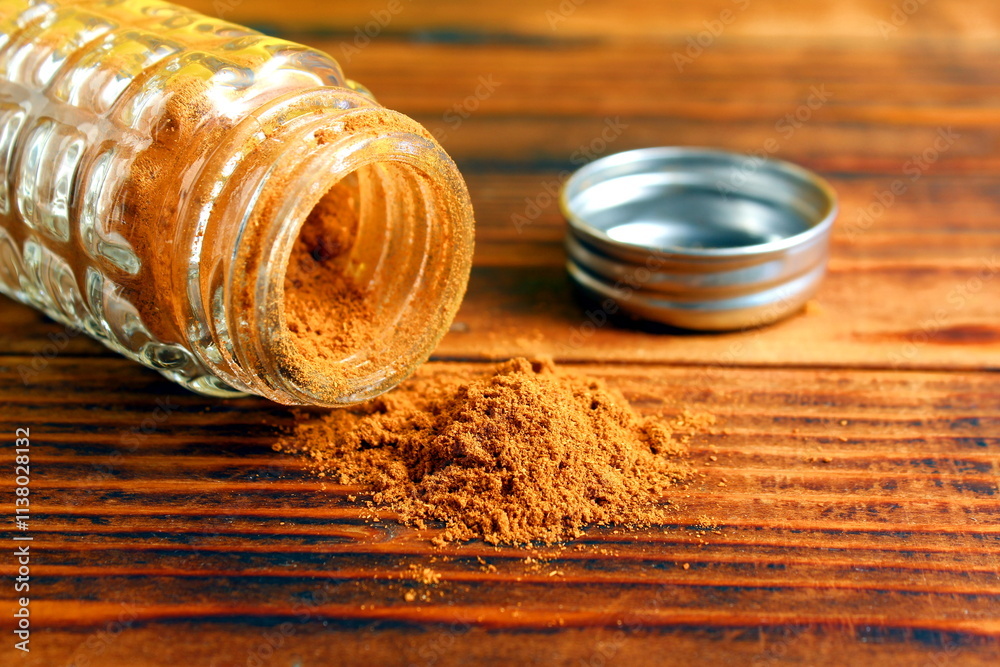 A glass pepper shaker lies with scattered pepper on a wooden table. A glass pepper shaker lies with scattered pepper on a wooden table.