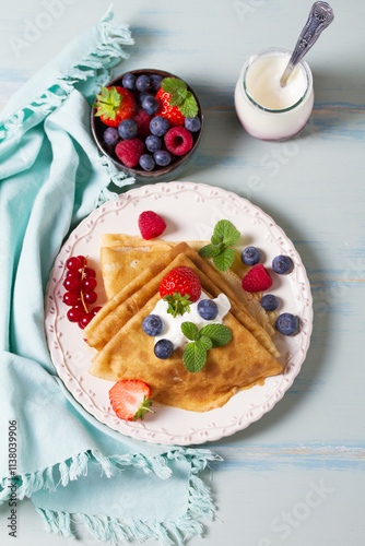 Crepes, thin pancake stack with yogurt and berries. Wrapped pancakes on a plate with copy space. High angle view