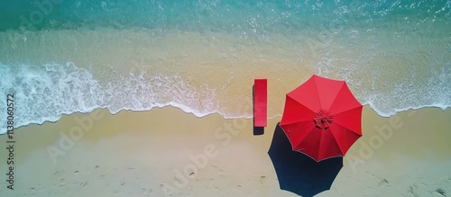 Aerial view of a red beach umbrella and chair on sandy shore showcasing a serene vacation scene at the sea.
