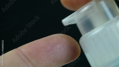 Close-up video showing a luxurious cream being dispensed from an airless bottle onto a finger, captured in ultra-macro detail against a sleek black background. Ideal for skincare, cosmetics, or beauty