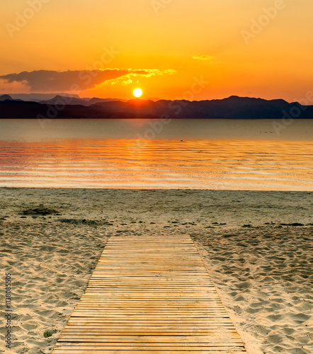 Coastal landscape with wooden footpath leading to a sandy shore of the sea or...