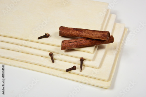raw yeast pastry slices on a white background with spices. Flat dough plates. puff pastry. puff frozen dough for baking