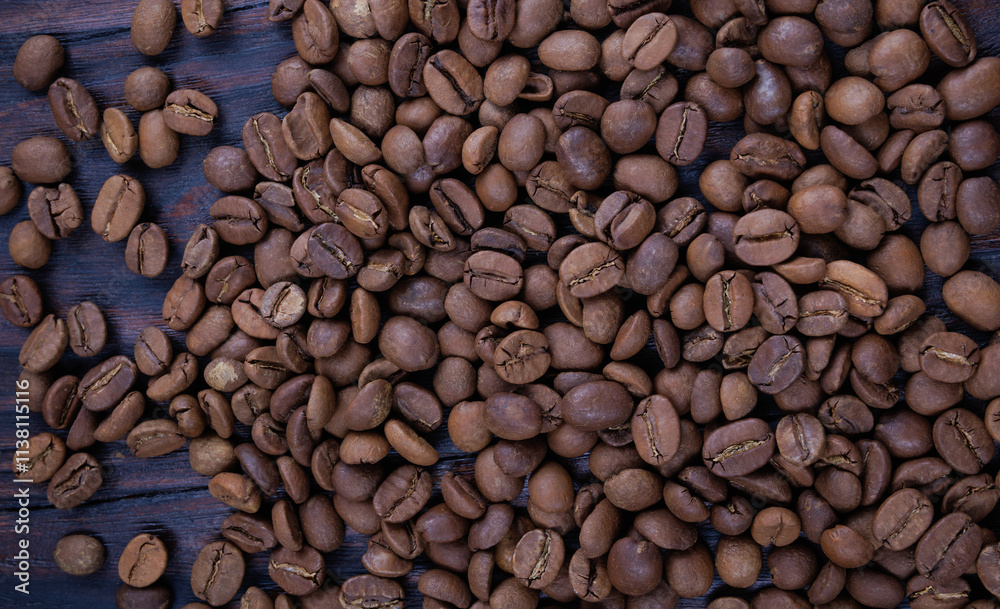 Background of roasted coffee beans scattered on a wooden surface. Background of roasted coffee beans scattered on a wooden surface.