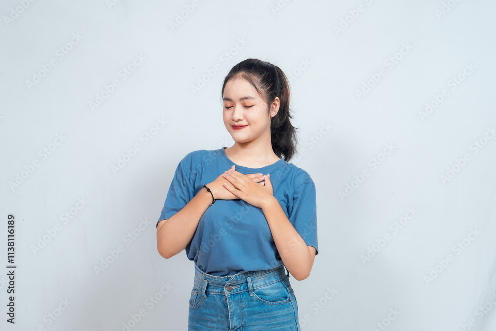 Happy mindful thankful young woman holding hands on chest smiling isolated on white background feeling no stress, gratitude, mental health balance, peace of mind concept. Happy mindful thankful young woman holding hands on chest smiling isolated on white background feeling no stress, gratitude, mental health balance, peace of mind concept.