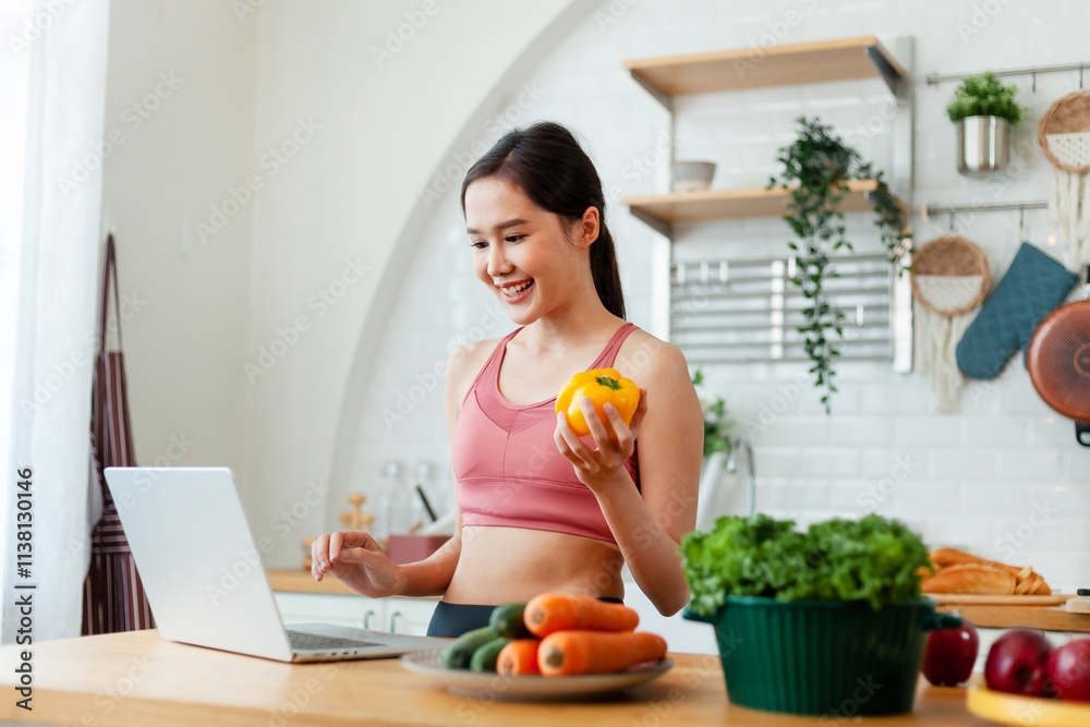 A woman is smiling while holding a pepper and a laptop. She is in a kitchen with a variety of vegetables, including carrots and broccoli A woman is smiling while holding a pepper and a laptop. She is in a kitchen with a variety of vegetables, including carrots and broccoli