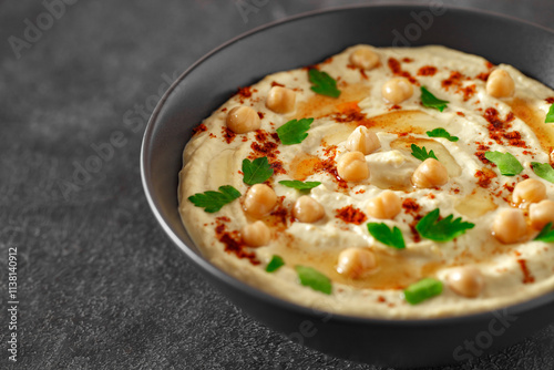 hummus with oil and chickpeas in a dark bowl, selective focus photo