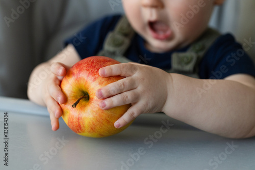 Little child with open mouth is ready to bite big ripe apple . Closeup, selective focus.