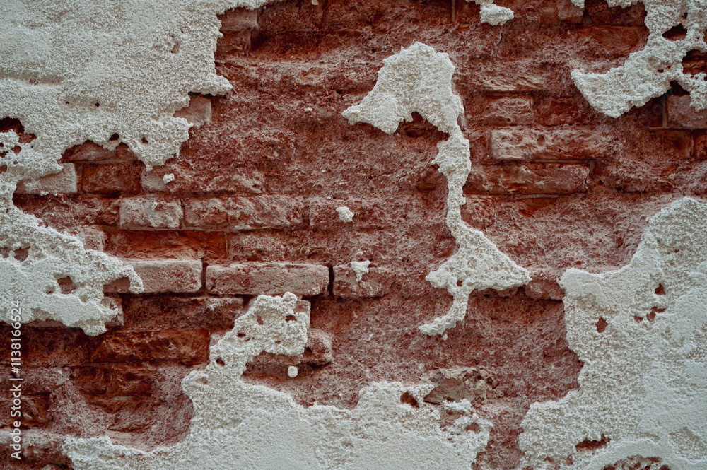Brick wall with pieces of plaster. Wall of an old building in need of renovation. Aged wall texture of brick building close up. Grunge background with red and white blocks and layers of cement stucco