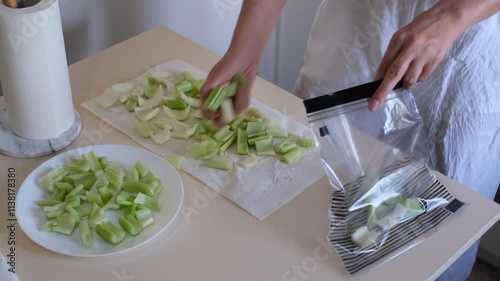 Housewife putting celery cubes in a freezer bag