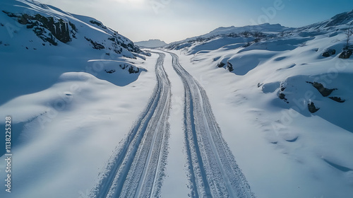 Verschneite Bergstraße mit tiefen Fahrspuren durch Winterlandschaft photo