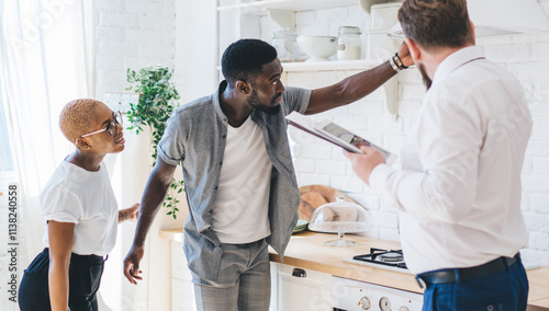 Konstfotografi Confident estate agent showing kitchen to African American attentive couple