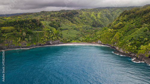 Hawaiian Island of Maui and a black sand beach embedded in a green rain forest landscape 