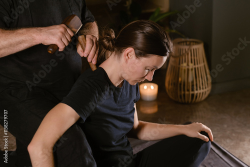 Male master giving Thai Toksen massage to girl in massage room. A girl gets a relaxing Thai back massage with a Toxen massage kit photo