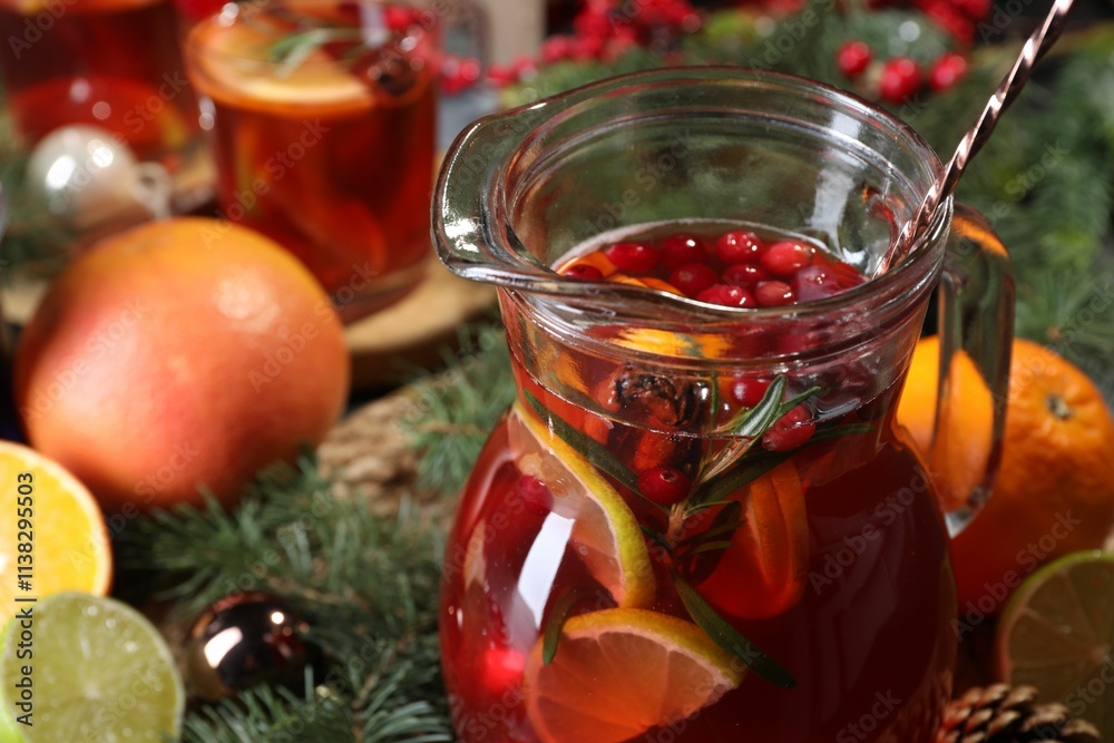 Tasty punch drink in glass jug, ingredients and Christmas decor on table, closeup Tasty punch drink in glass jug, ingredients and Christmas decor on table, closeup