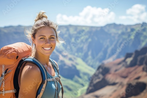 A smiling woman hiker with a backpack enjoys a scenic mountain view on a sunny day.