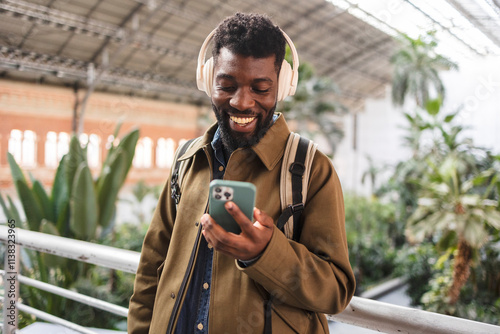 Smiling tourist listening to music and browsing smartphone in atocha station