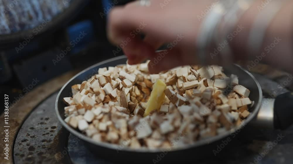 A pan of mushrooms is on a stove. The mushrooms are brown and white. The pan is on a metal surface A pan of mushrooms is on a stove. The mushrooms are brown and white. The pan is on a metal surface