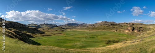 Under the warm sun of a spring afternoon, the scenic Romanian countryside unfolds, displaying a splendid mountainous landscape with verdant grassy fields and gently rolling hills, embodying the charm