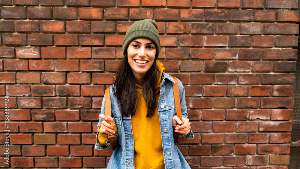 Smiling young woman looking at the camera with her hands on her backpack Smiling young woman looking at the camera with her hands on her backpack