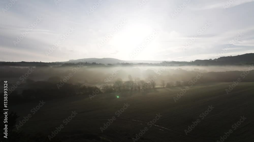 A foggy, misty morning with a sun rising in the background. The sky is overcast and the sun is barely visible A foggy, misty morning with a sun rising in the background. The sky is overcast and the sun is barely visible
