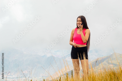 una mujer atractiva con top y short sosteniendo un teléfono celular en la mano en el campo, una linda chica mirando la pantalla del móvil. representación de conexión con la naturaleza photo