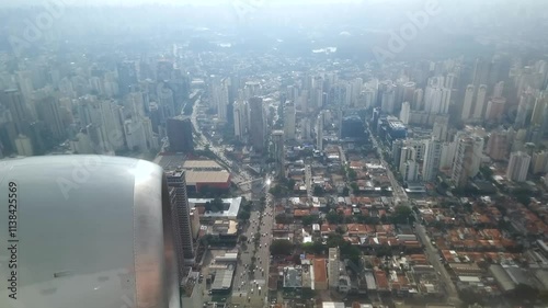 View through the airplane window during a flight over the city of São Paulo, flying close to the buildings arriving at the landing destination, Congonhas airport.
