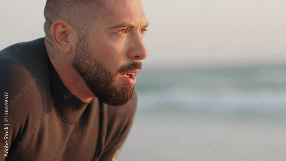 A tired surfer catches his breath after a surf session on the beach at sunset. He's exhausted but happy. A tired surfer catches his breath after a surf session on the beach at sunset. He's exhausted but happy.