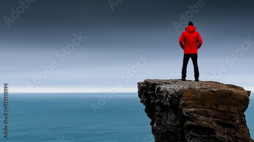 Lone Figure on Clifftop: A solitary figure stands on a rocky cliff edge, gazing out at the vast expanse of the ocean, a powerful symbol of resilience and determination. photo