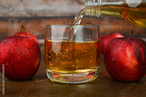Pouring apple cider vinegar in a glass cup.