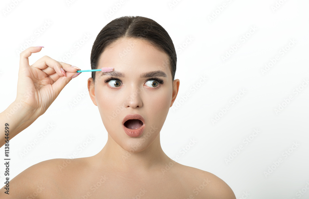 Young beautiful brunette girl with natural makeup and laminated brows holds brush for eyebrow corrections. Eyebrow correction and perm lamination procedure. Young beautiful brunette girl with natural makeup and laminated brows holds brush for eyebrow corrections. Eyebrow correction and perm lamination procedure.