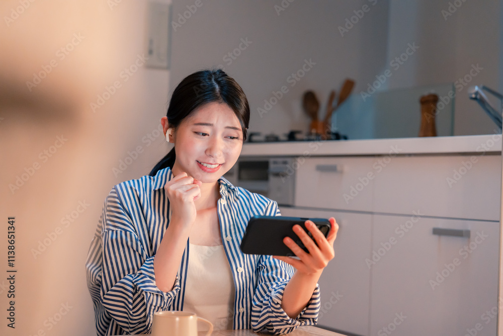 夜に家でスマホでスポーツ観戦をする若い女性 夜に家でスマホでスポーツ観戦をする若い女性