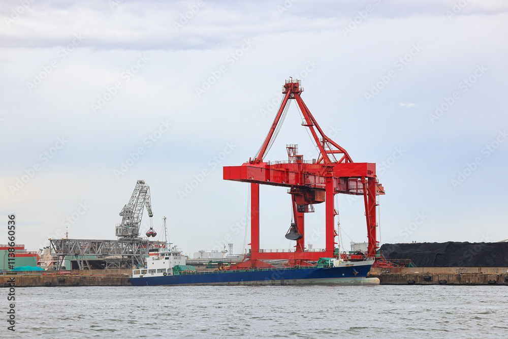 Large crane works on large coal stockpile and container crane at Industrial port for cargo container ship. Cargo transportation and activity at modern shipping container terminal. Large crane works on large coal stockpile and container crane at Industrial port for cargo container ship. Cargo transportation and activity at modern shipping container terminal.