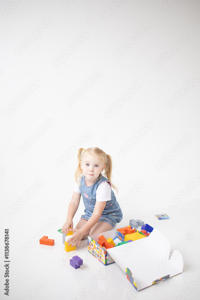 Educational Toys: The Child Develops Motor Skills With The Help Of Colorful Cubes on a white background. The girl is playing with cubes Educational Toys: The Child Develops Motor Skills With The Help Of Colorful Cubes on a white background. The girl is playing with cubes