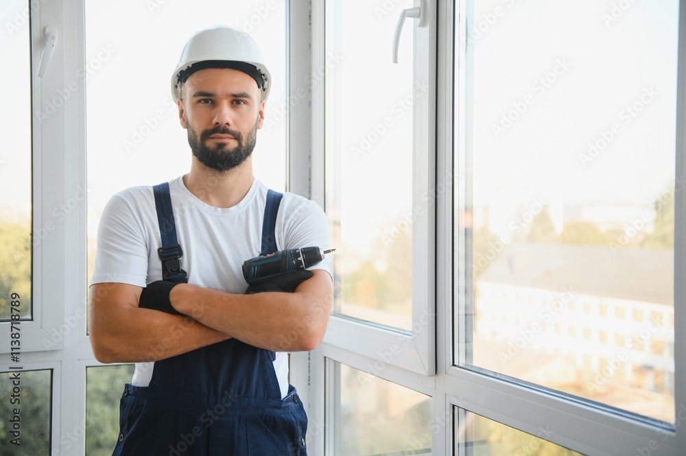 Construction worker repairing plastic window with screwdriver indoors, space for text. Construction worker repairing plastic window with screwdriver indoors, space for text.