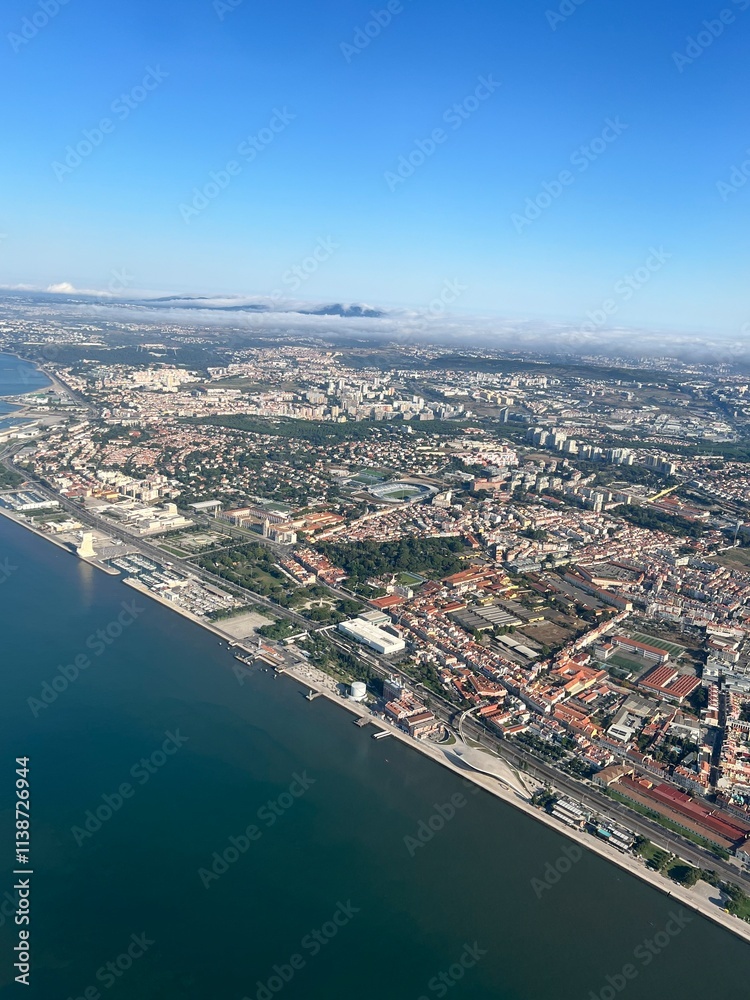Fototapeta premium Belem, Lisbon, Portugal - 26th April 2024 - Aerial view of historic Belem district along Tagus River, featuring iconic MAAT museum, maritime promenade, and mix of modern and historic architecture.