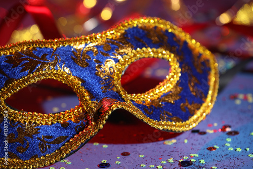 Beautiful carnival mask and confetti on color background, closeup photo