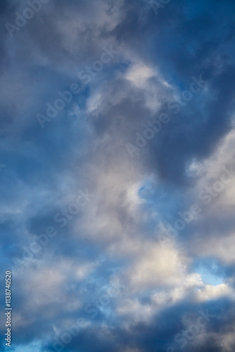 Soft sunlight highlights gray winter clouds against a bright blue sky. blur