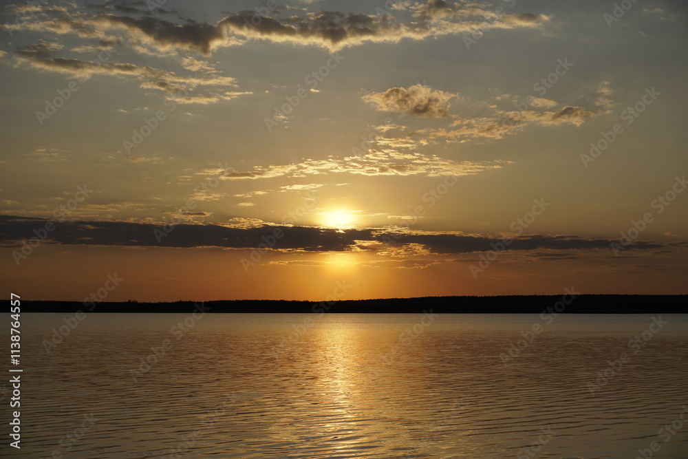 Naklejka premium Quiet evening after a sultry day. Beautiful sunset over the lake. Reflection and horizon. Evening dim soft sun