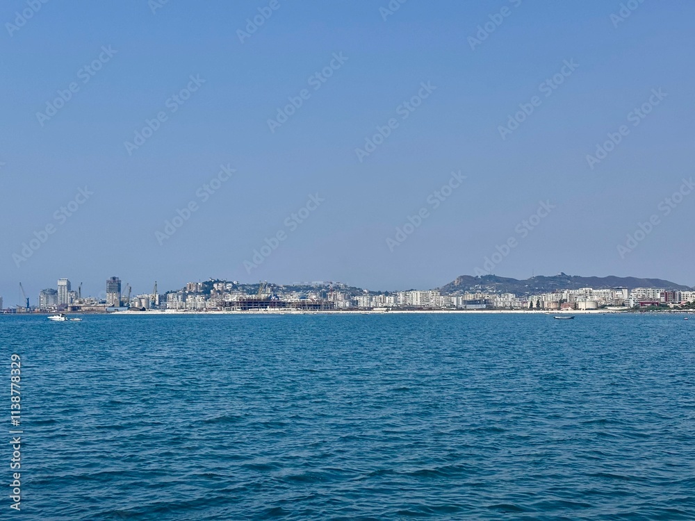 view of a coast of Durres in Albania with waterfront buildings and its port on a sunny summer day
view of a coast of Durres in Albania with waterfront buildings and its port on a sunny summer day