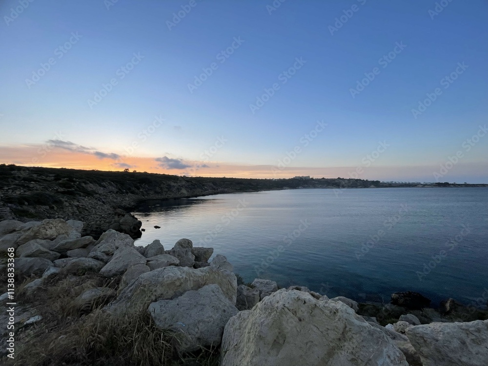 Rocky Coastline with Calm Sea and Vibrant Sunset in Cyprus Rocky Coastline with Calm Sea and Vibrant Sunset in Cyprus