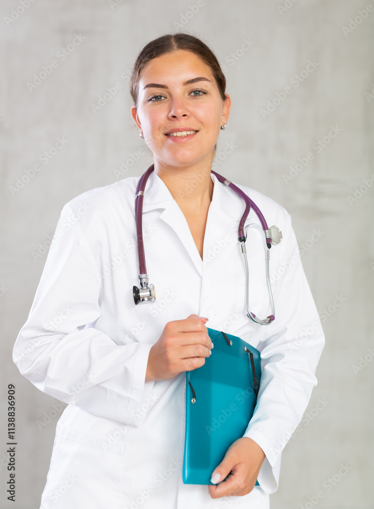 Smiling female doctor standing holding file with papers Smiling female doctor standing holding file with papers