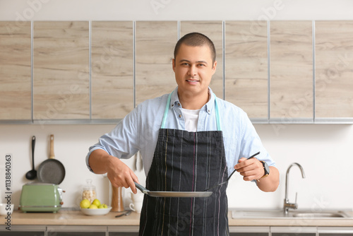 Smiling young man in apron ...