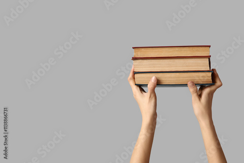 Hands holding books on grey  background