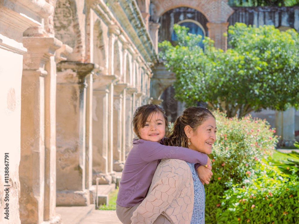 Latina grandmother holds her beautiful granddaughter and poses in front of the camera for a souvenir photo. Latina grandmother holds her beautiful granddaughter and poses in front of the camera for a souvenir photo.