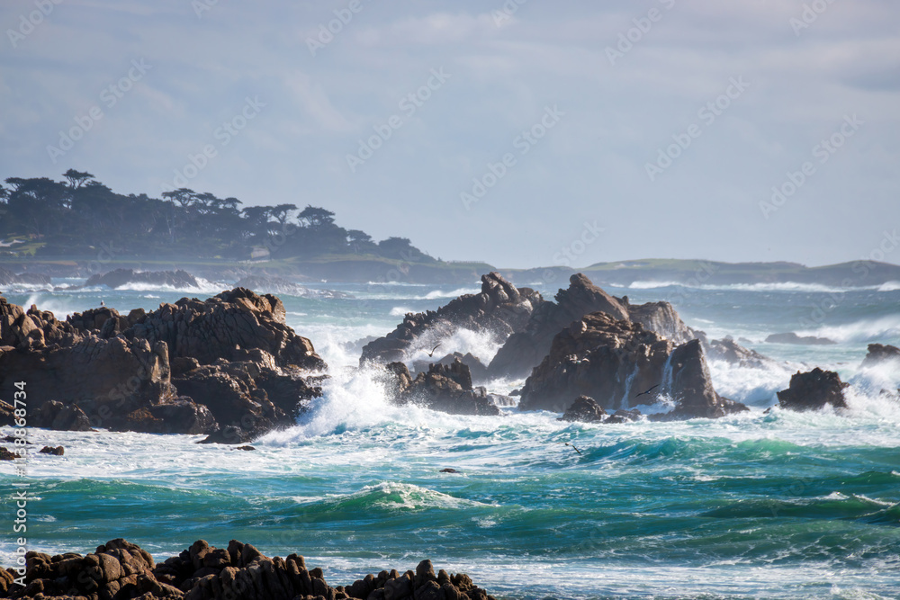 Scenic view rocky Pacific Ocean coast along 17-Mile-Drive looking south, Del Monte Forest, California, USA against blue sky with clouds