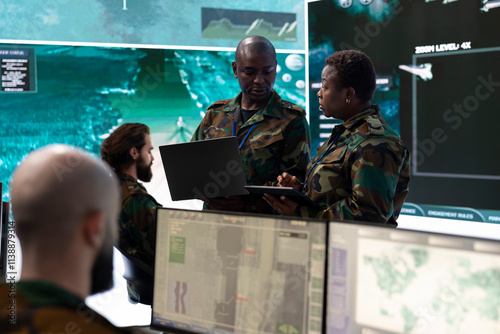Obraz na plátně Female infantry unit soldier and new recruit discuss about mission details, gathering intelligence via radar surveillance on a big screen