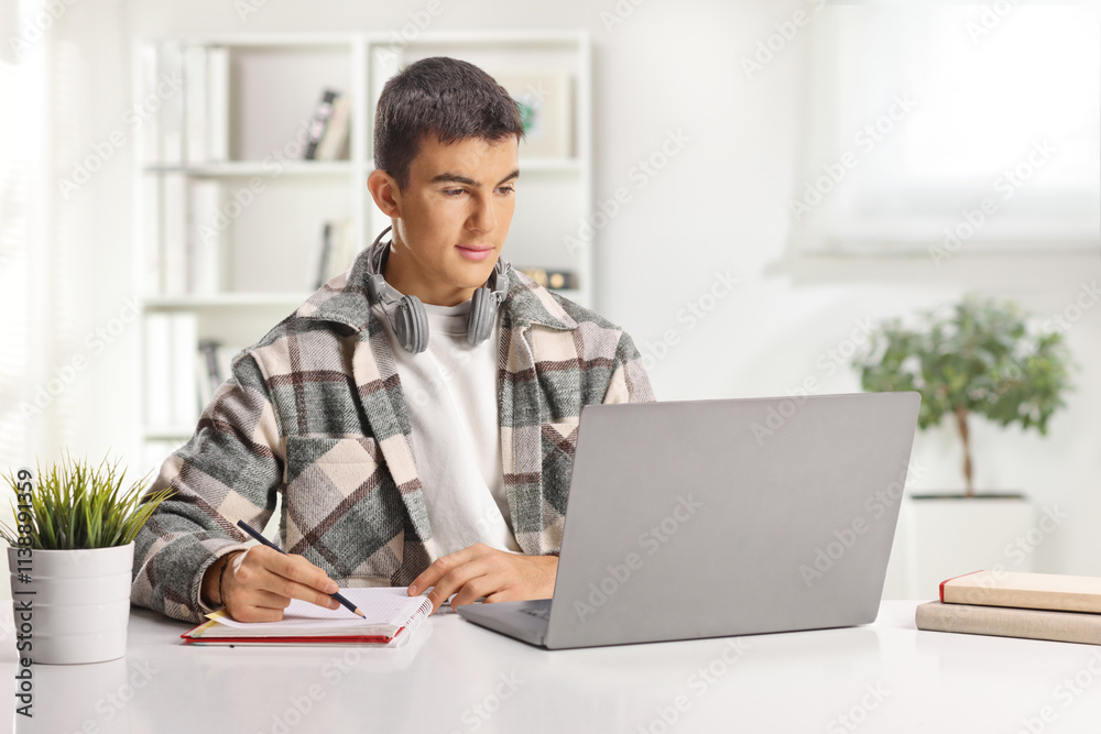 Student with headphones writing and browsing on a laptop computer at home Student with headphones writing and browsing on a laptop computer at home