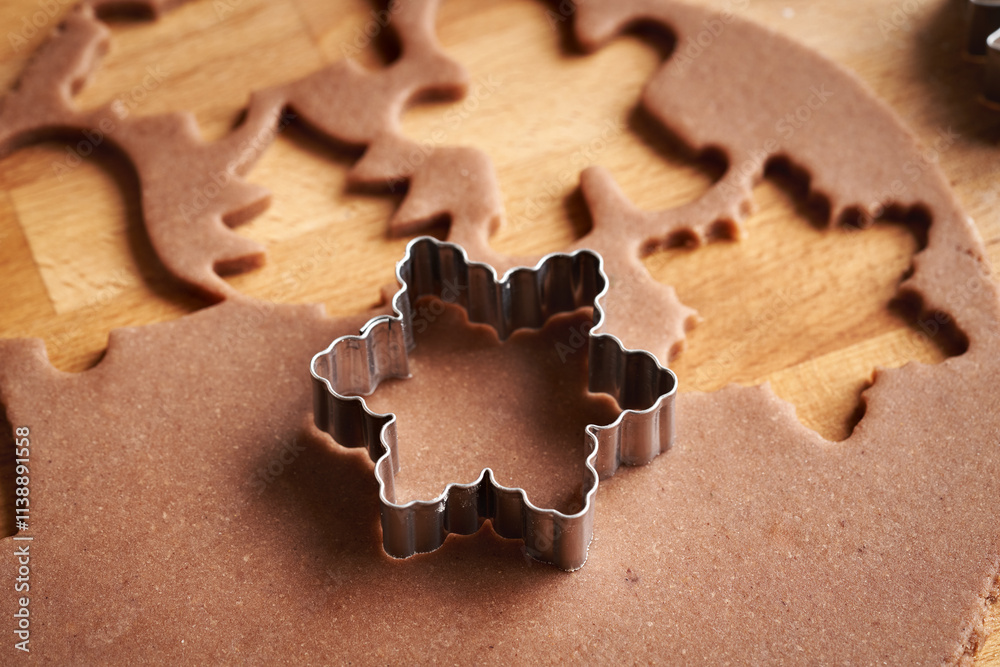 Fototapeta premium Cutting out star shapes from raw pastry dough - preparation of gingerbread Christmas cookies